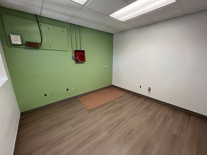 Empty room with green wall and exposed electrical work